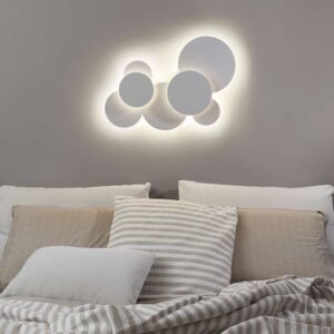 Ideal Lux Cloud PL D74 285207 е монтиран на стена над легло и осветява индиректно пространството около белите кръгли елементи