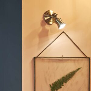 Апликът Ideal Lux Barber AP1 159997 в месингов цвят е монтиран над рамкирана картина и насочен към нея