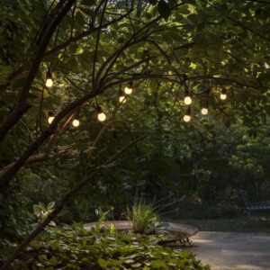 Ideal Lux Fiesta SP10 246796 с десет светещи крушки е окачен сред клоните на дървета в градина