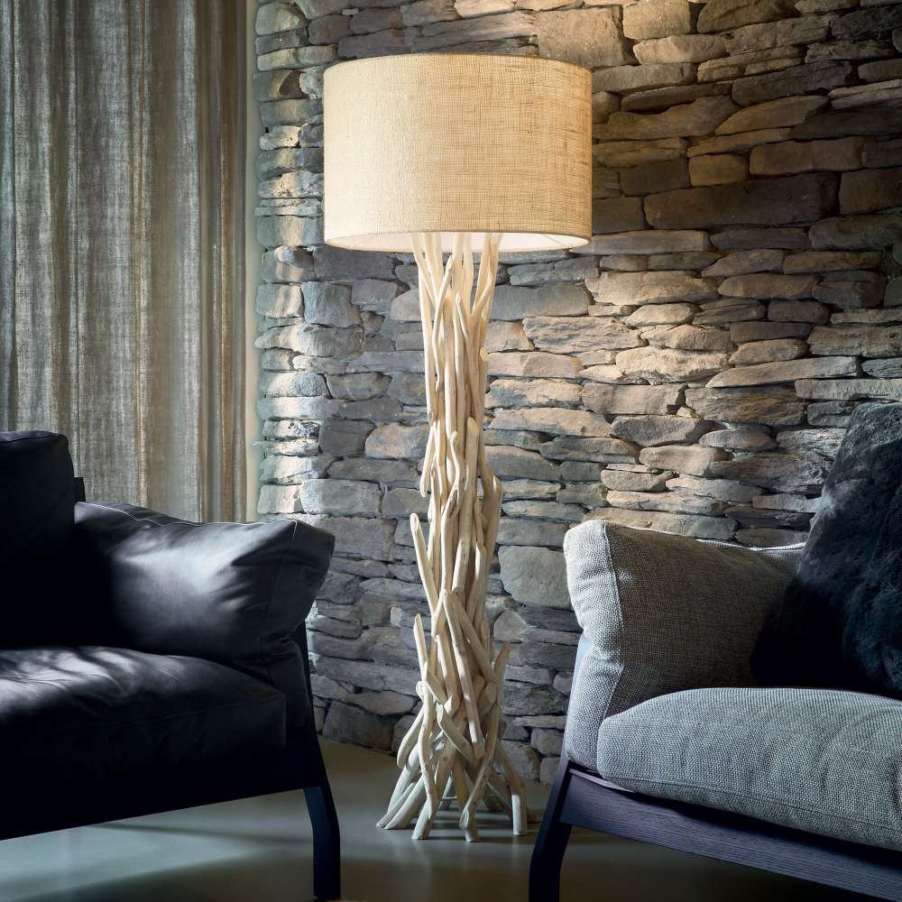 Лампионът Ideal Lux Driftwood PT1 148939 с бежов абажур е поставен до диван пред каменна стена